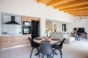 A modern kitchen with a built-in oven and a dining area with a round table and chairs. - Villa Pietra di Mare-Yeni-Nidri-Lefkada (Geni)