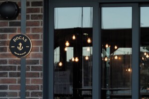 A brick wall with a circular sign that reads 'DOCAS' and 'LISBON TAGUS' with an anchor symbol. - Docas Hotel Lisbon (Lisbon)