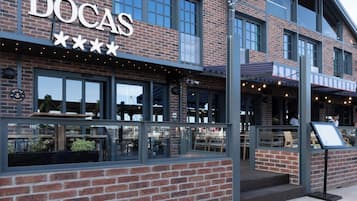 A brick building with a sign reading 'DOCAS' and outdoor seating.