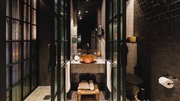 A narrow, dark hallway with a tiled wall and a bench with a towel.