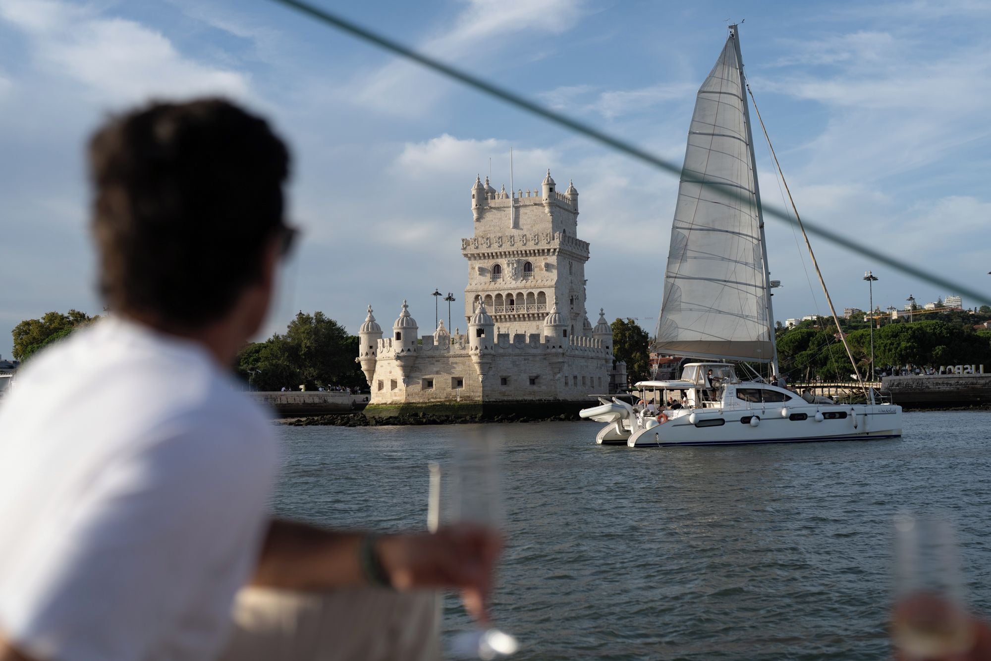 Una torre histórica con múltiples cúpulas y un velero en primer plano.