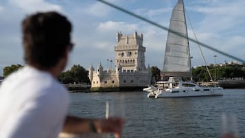 Una torre histórica con múltiples cúpulas y un velero en primer plano.