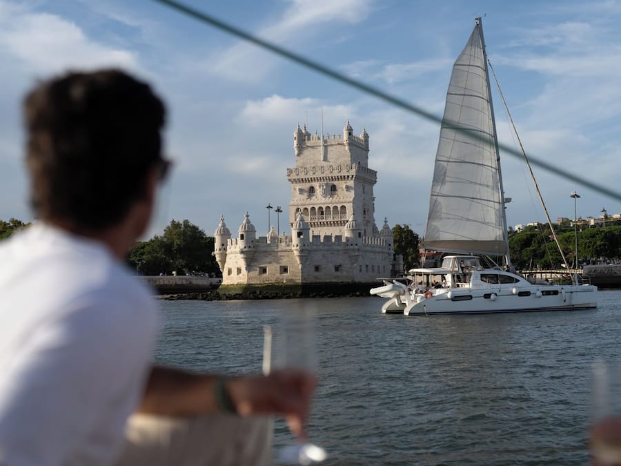 Una torre histórica con múltiples cúpulas y un velero en primer plano.