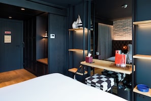 Une chambre d’hôtel moderne équipée d’un lit, d’un bureau avec un ordinateur, d’un téléphone et d’un miroir.