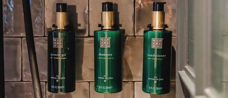 A bathroom with a tiled wall and three bottles of lotion.
