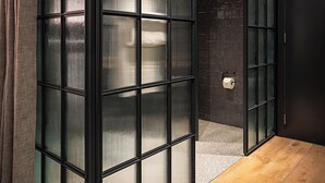 A room with large glass doors, a wooden floor, and a brick wall. - Docas Hotel Lisbon (Lisbon)