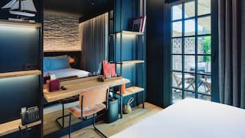 A modern room with a bunk bed, a desk with a chair, a bookshelf, and a window with a view of the outside.