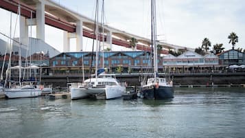 Un puerto deportivo con varias embarcaciones amarradas, un puente en primer plano y edificios con terrazas al fondo.