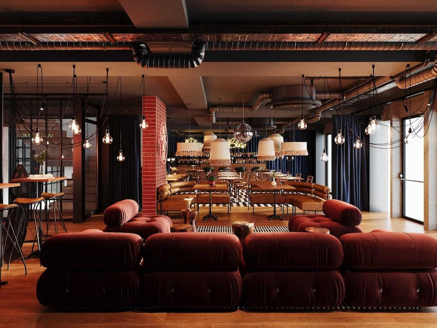 A modern interior with a central seating area, exposed ductwork, and hanging pendant lights.
