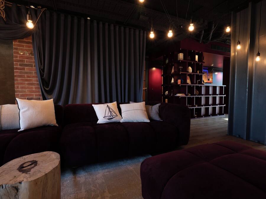 Una sala de estar moderna con un sofá de color oscuro, una mesa de centro de madera y una estantería al fondo.