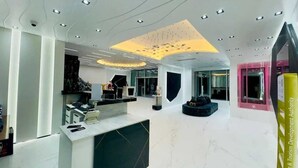 A modern hotel lobby with a reception desk, seating area, and a large digital display.