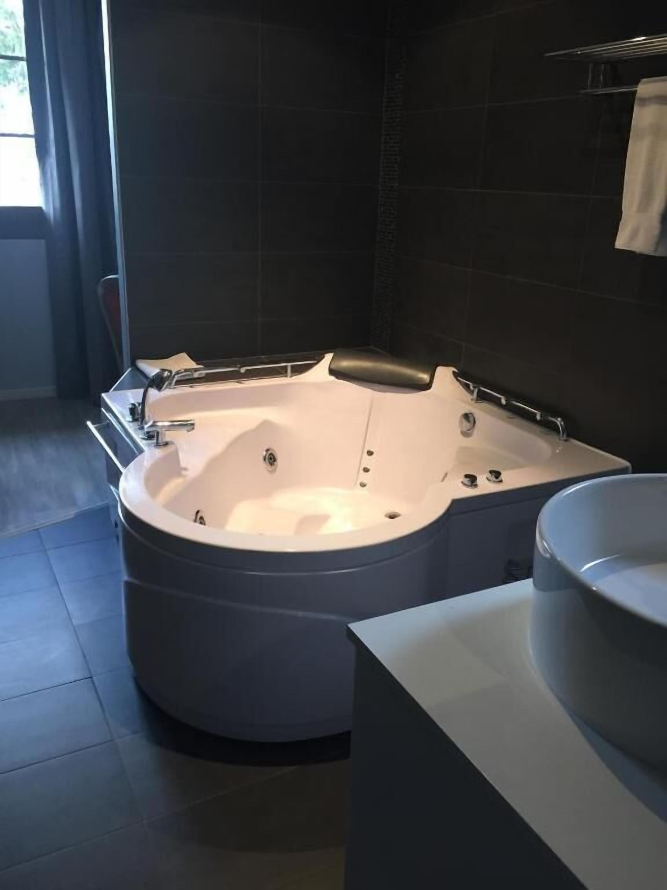 Un baño moderno con una bañera independiente, un espejo grande y un lavamanos blanco.
