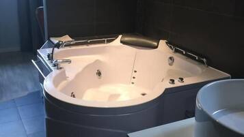 Un baño moderno con una bañera independiente, un espejo grande y un lavamanos blanco.