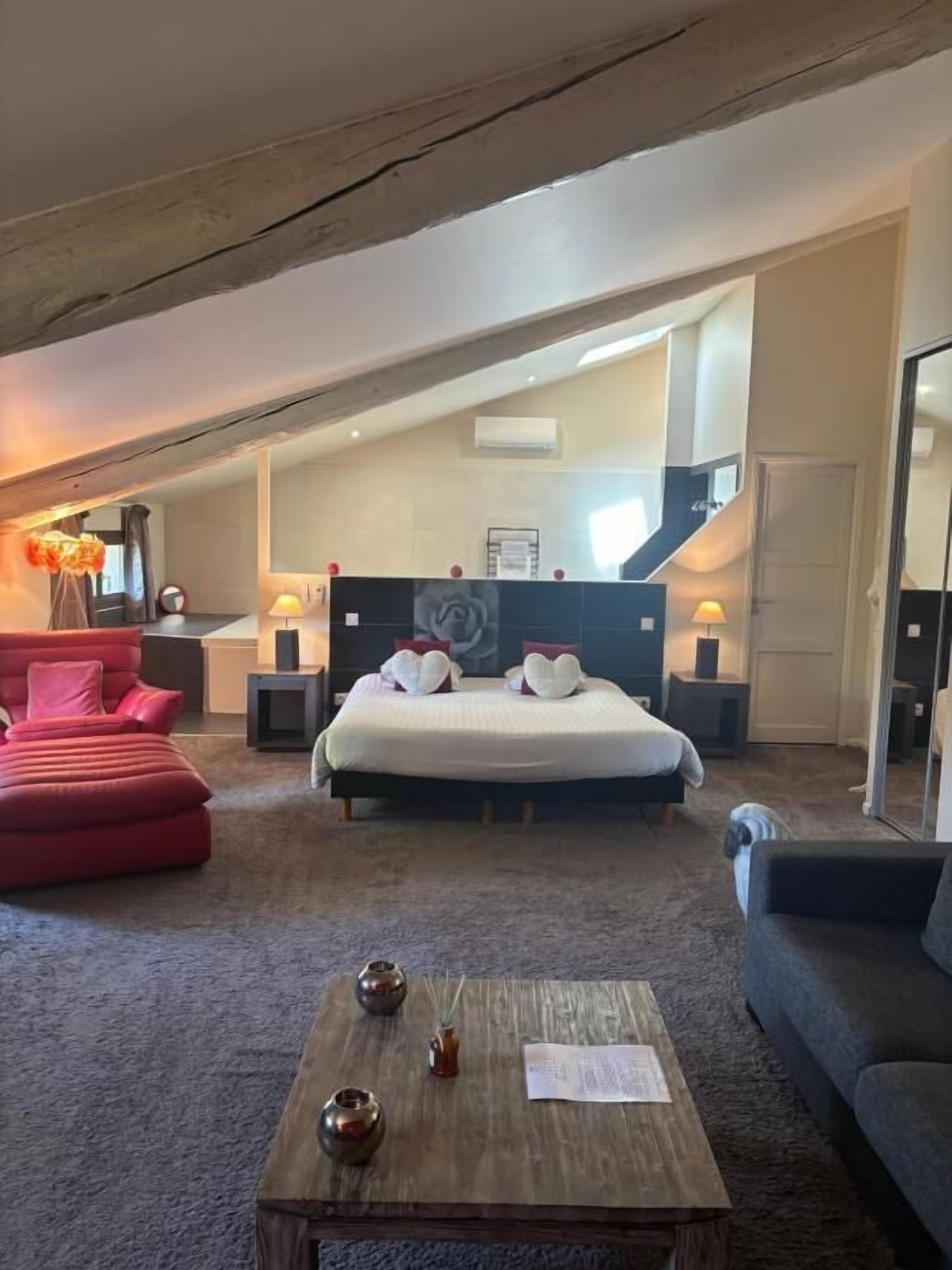 Un dormitorio con una cama grande, una mesita de centro de madera y un sofá rojo.