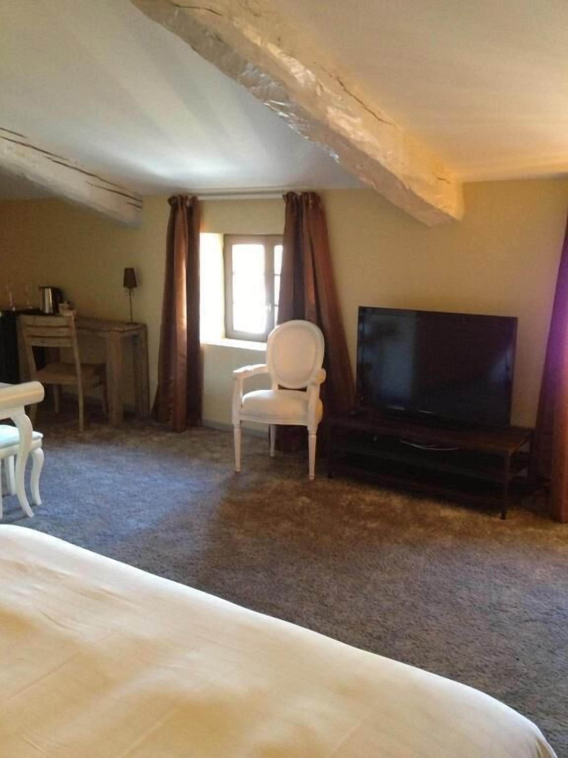 Een kamer met een bed, een televisie, een bureau en een stoel.