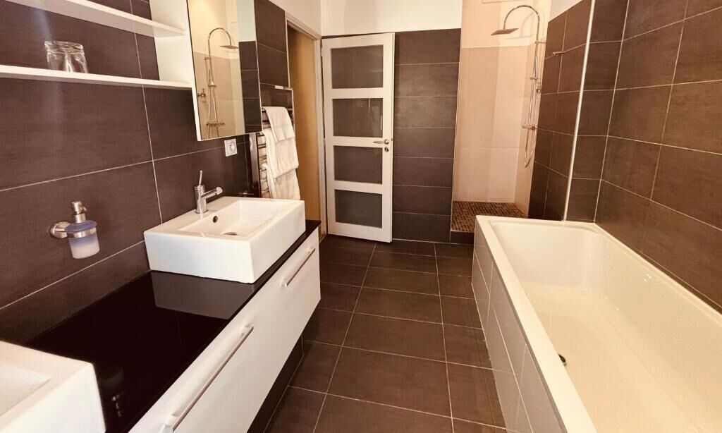 Un bagno moderno con un lavandino bianco, una vasca e uno spazio doccia.