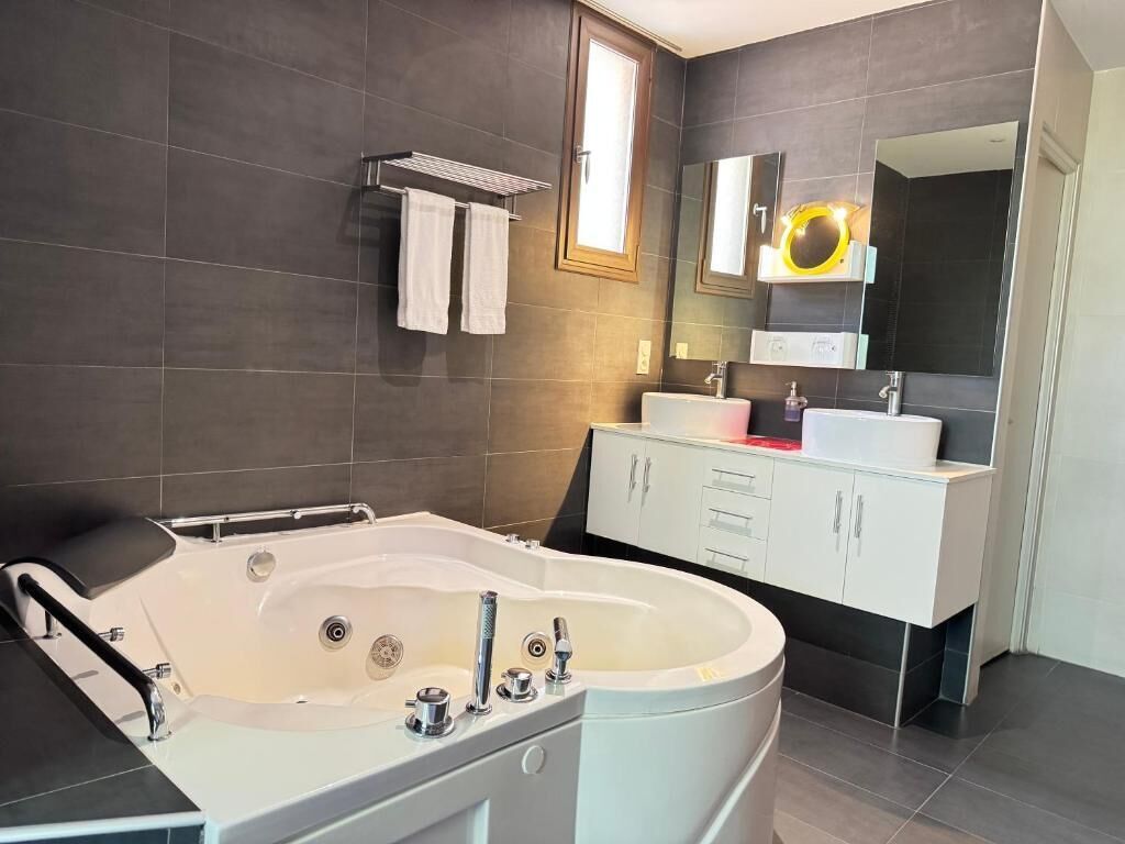 Un baño moderno con una bañera independiente, un tocador con espejo y un perchero para toallas.