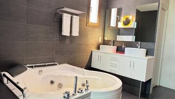 Un baño moderno con una bañera independiente, un tocador con espejo y un perchero para toallas.