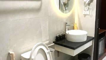 Un baño moderno con inodoro, lavabo, espejo y toallero.