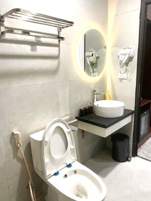 A modern bathroom with a toilet, sink, mirror, and towel rack. - Lucky Eden Noi Bai Hotel (Hanoi)