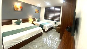 Habitación de hotel con dos camas, una mesita, un televisor y obras de arte en las paredes.