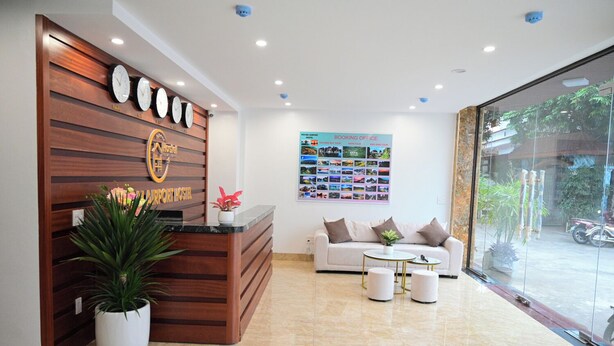 Zona de recepción de un hotel con un mostrador de madera, un sofá y una mesa de centro.