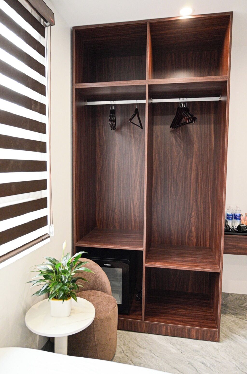 Une armoire avec plusieurs compartiments, une petite table avec une plante et un meuble pour la télévision.