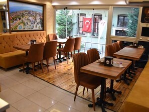 Een restaurant met uitzicht op een stadsbeeld, een bank en tafels met stoelen.