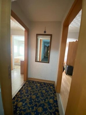 A hallway with a patterned carpet, a mirror on the wall, and a door leading to another room. - Timeks Hotel (Istanbul)