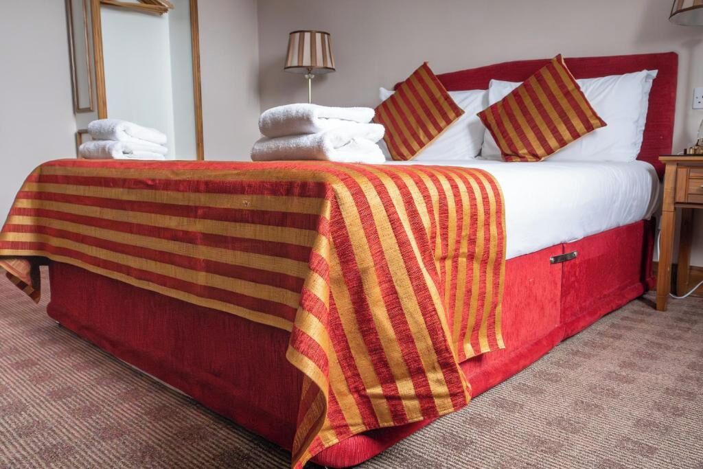 Quarto de hotel com cama, luminária e toalhas.