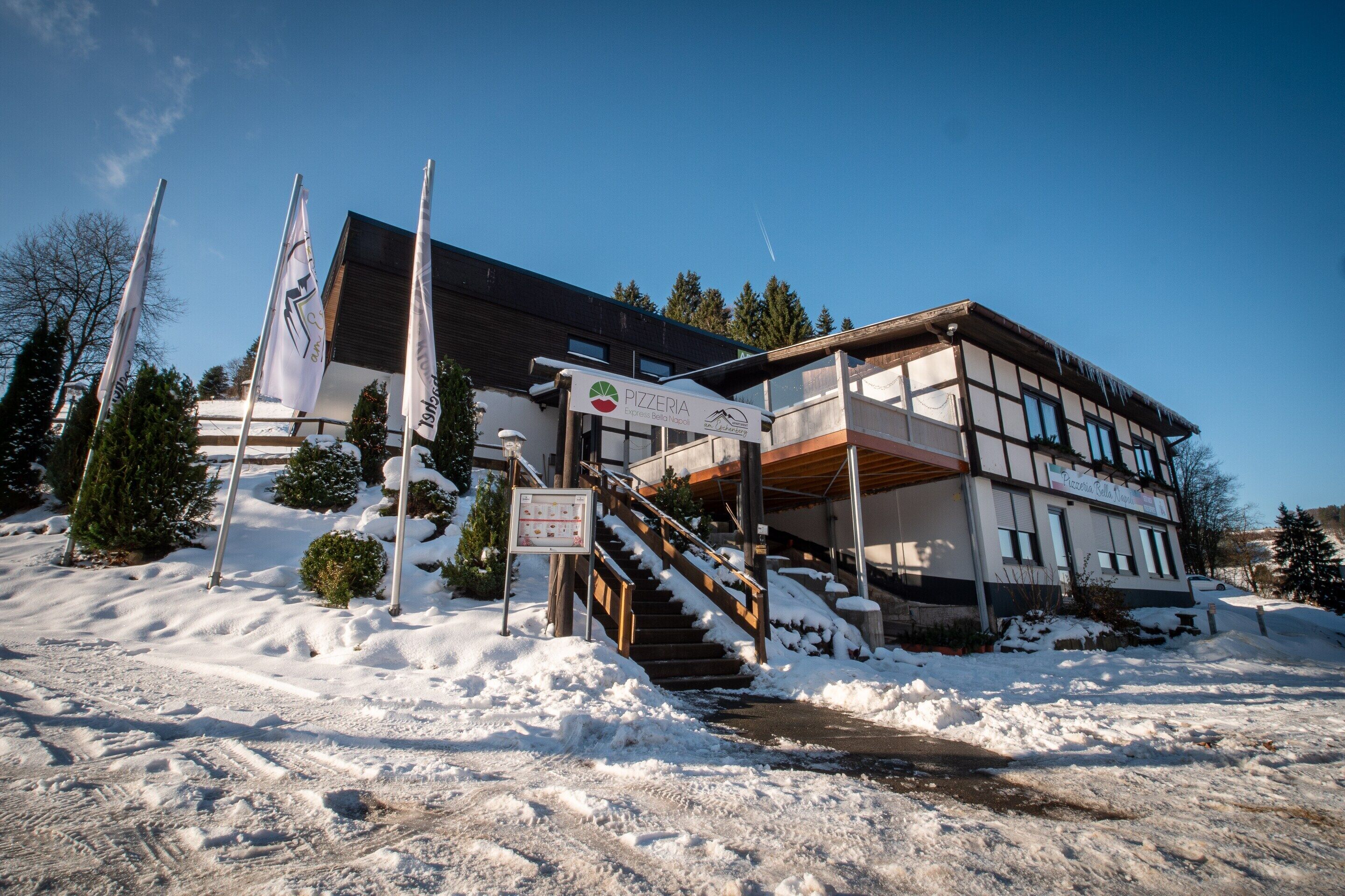 A building with a sign for 'Pizzeria Express,' a staircase, and snow-covered surroundings.