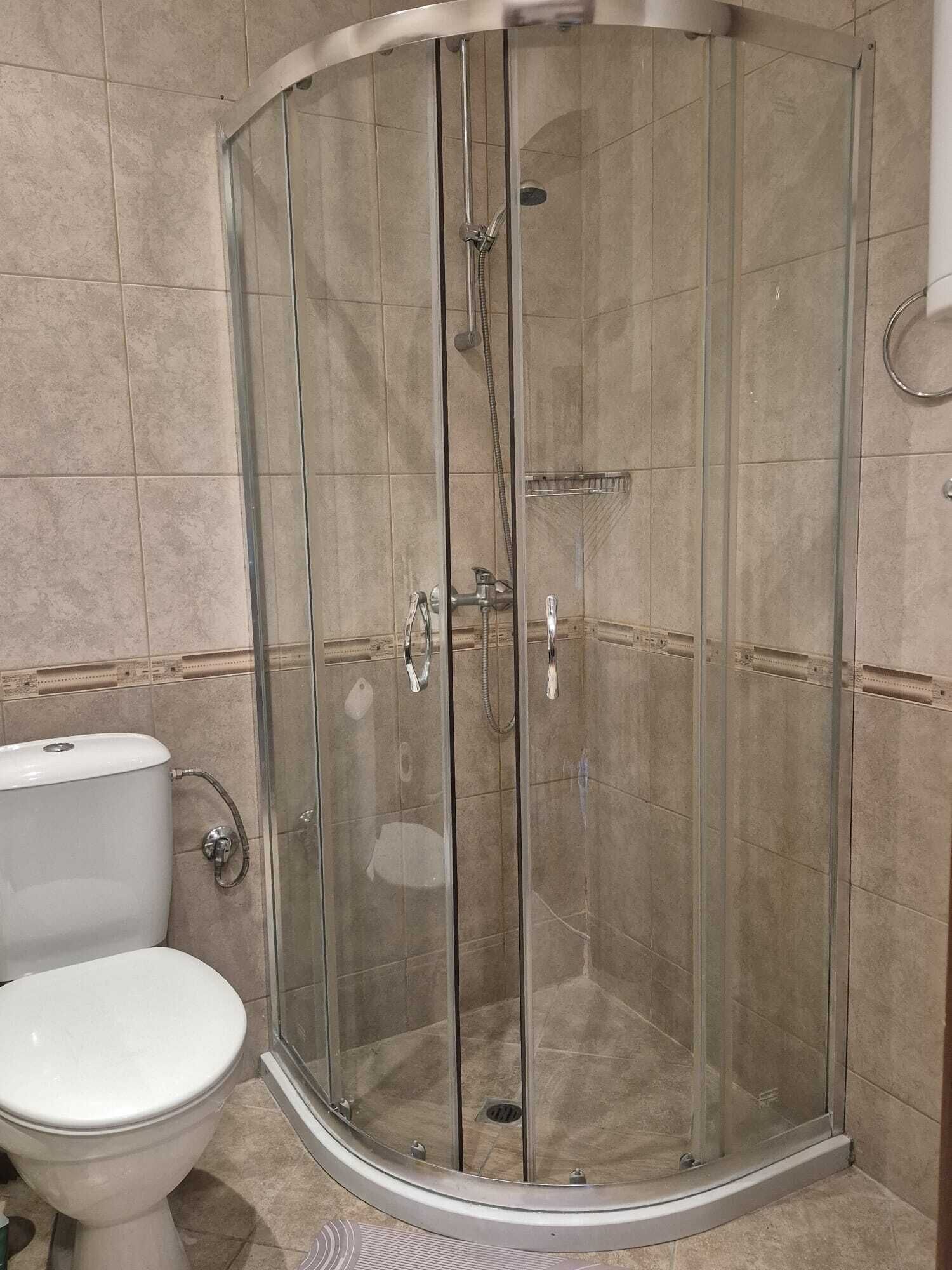 A glass-enclosed shower with a toilet to the left.