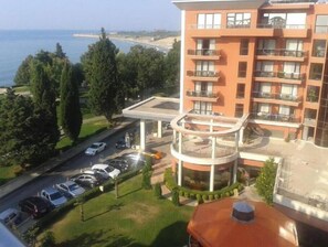 A multi-story building with balconies, a parking area, and a view of the sea. - Sea view & Beach Apartment (Nessebur)
