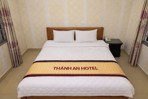 Une chambre d’hôtel avec un lit, une table de chevet et des rideaux.