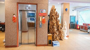 Un vestíbulo de hotel con un mostrador de recepción, una gran escultura de madera, una estatua y un extintor.