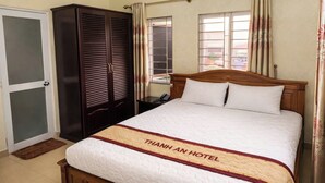 Una habitación de hotel con cama, armario, ventana con cortinas y puerta.