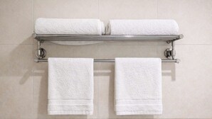 Un baño con dos toallas blancas colgadas en un toallero de metal.