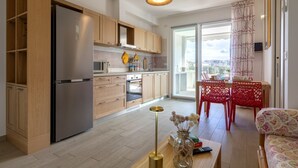Cocina moderna con armarios de madera, un refrigerador de acero inoxidable y un comedor con sillas rojas y una mesa.