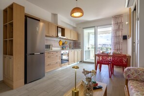 A modern kitchen with wooden cabinets, a stainless steel refrigerator, and a dining area with red chairs and a table. - Casa Eolo. Appartamento con terrazza e box privato. (Alghero)