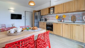 Una cocina moderna con armarios de madera, microondas y comedor con sillas rojas.