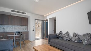 A modern living space with a kitchen, dining area, and a sofa with patterned cushions. - Adrina Grand Hotel (Skopelos)
