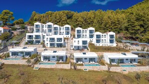 A modern resort with multiple white buildings, outdoor pools, and a hillside backdrop. - Adrina Grand Hotel (Skopelos)