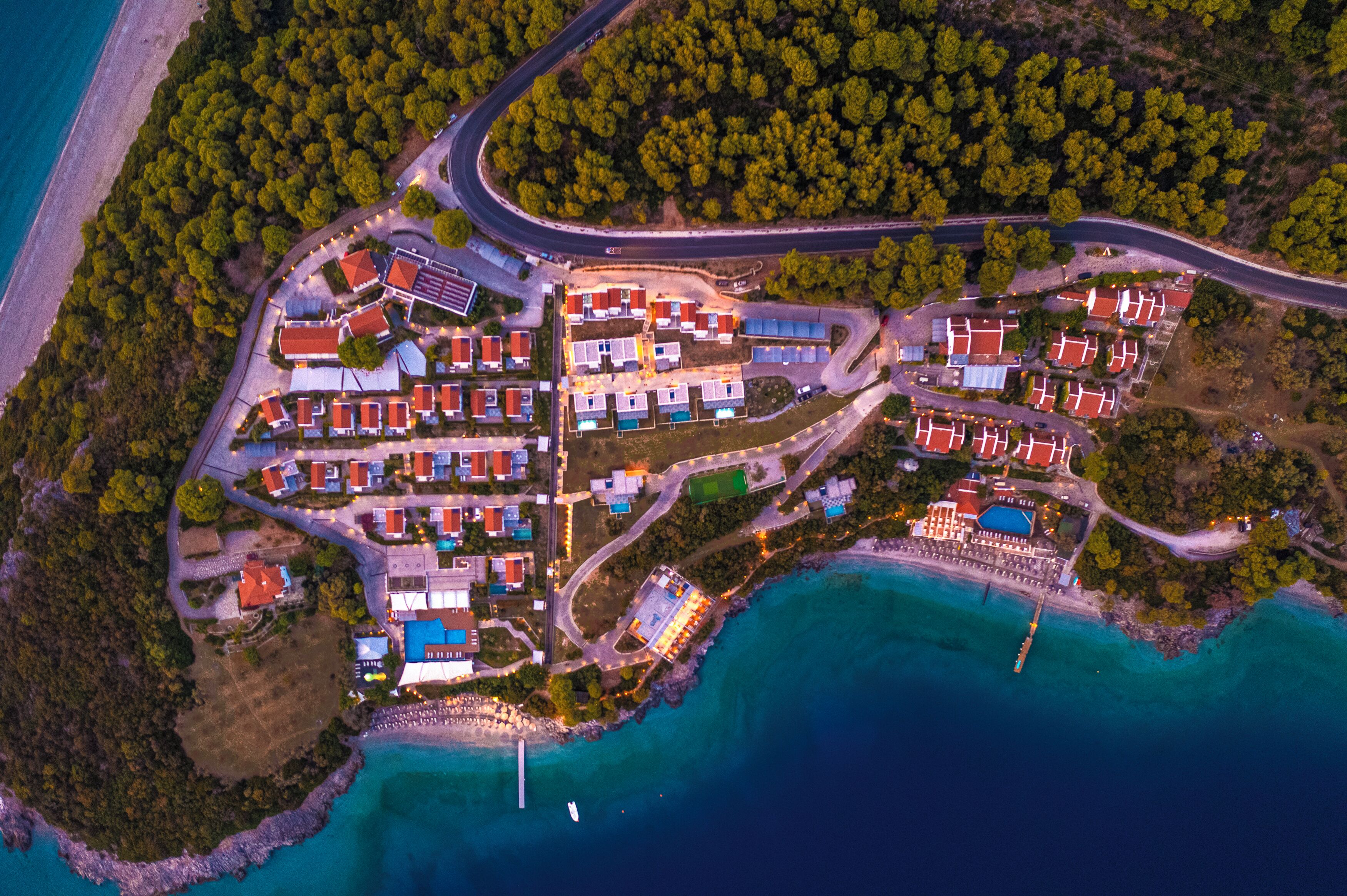 An aerial view of a coastal resort with multiple buildings, a marina, and a beach.