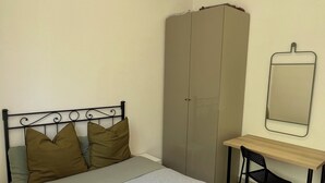 Ein Schlafzimmer mit Bett, Schreibtisch, Stuhl und Kleiderschrank.