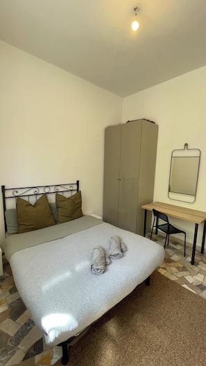 Ein Schlafzimmer mit Bett, Schreibtisch, Stuhl und Kleiderschrank.