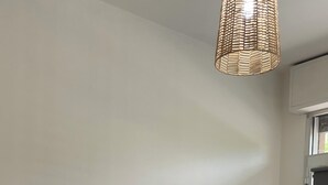 Ein Essbereich mit Holztisch, roten Stühlen, einer gewebten Pendelleuchte, einem an der Wand montierten Fernseher und einer Heizung.