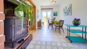 A dining area with a table and chairs, a fireplace, and a hanging light fixture. - Apartment Bijenica - surrounded by lush greenery (Vrbnik)