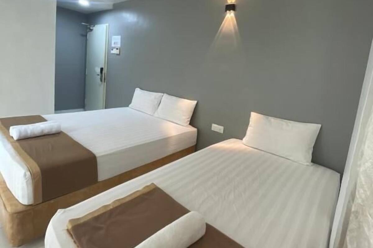 Una habitación de hotel con dos camas, una lámpara fijada a la pared y una puerta.