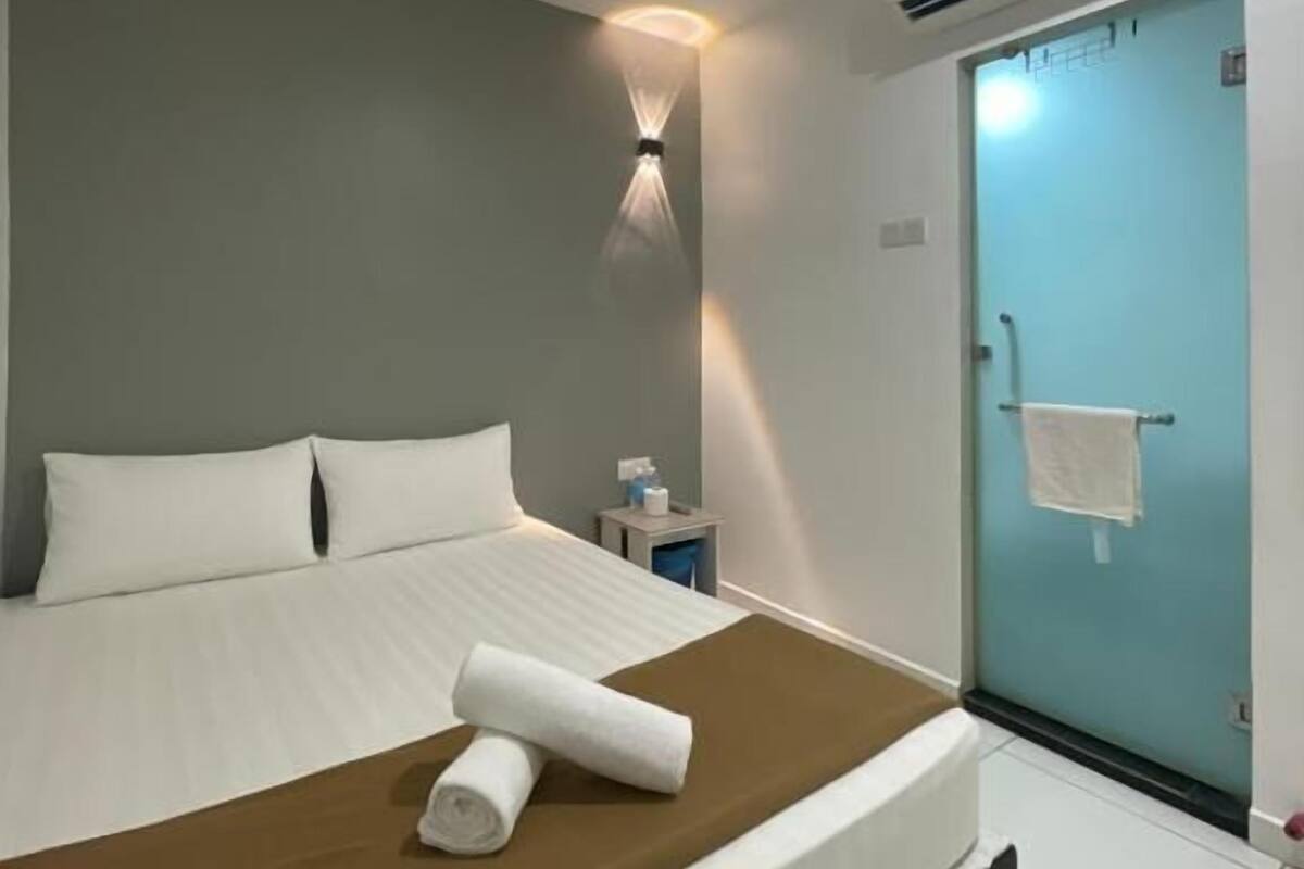 Habitación de hotel con cama, mesita de noche, aire acondicionado y una puerta.