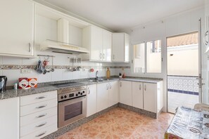 Une cuisine avec des meubles blancs, une cuisinière et un évier.